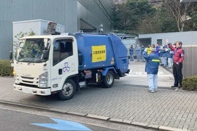 出発する清掃車を職員が見守っている画像